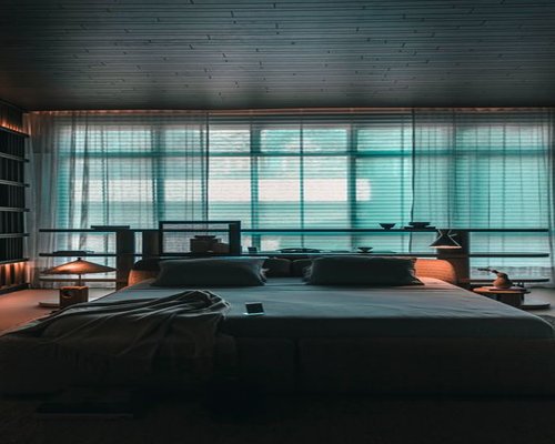 A serene bright minimalist bedroom layout with light beige sheets and window curtains creating a peaceful space optimized for restorative night sleep