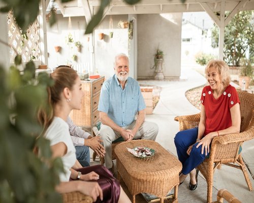 A group of people sitting casually in a beautiful warm outdoor patio sharing food and chatting comfortably during a family gathering