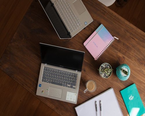 A warm professional wooden desktop workspace with notebooks, pens, and a small green plant reflecting a calm work environment